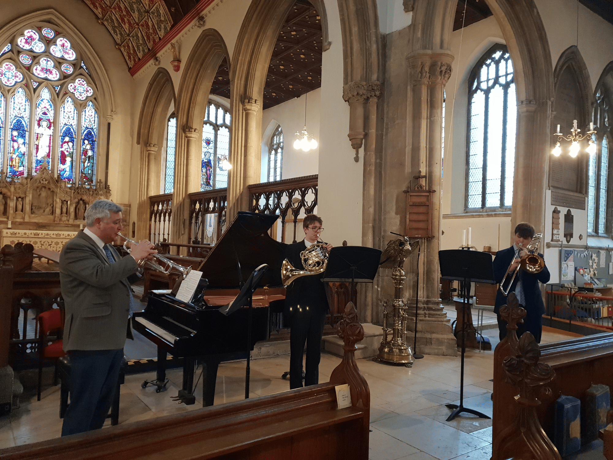 A trio of trumpet, horn and trombone perform in a church