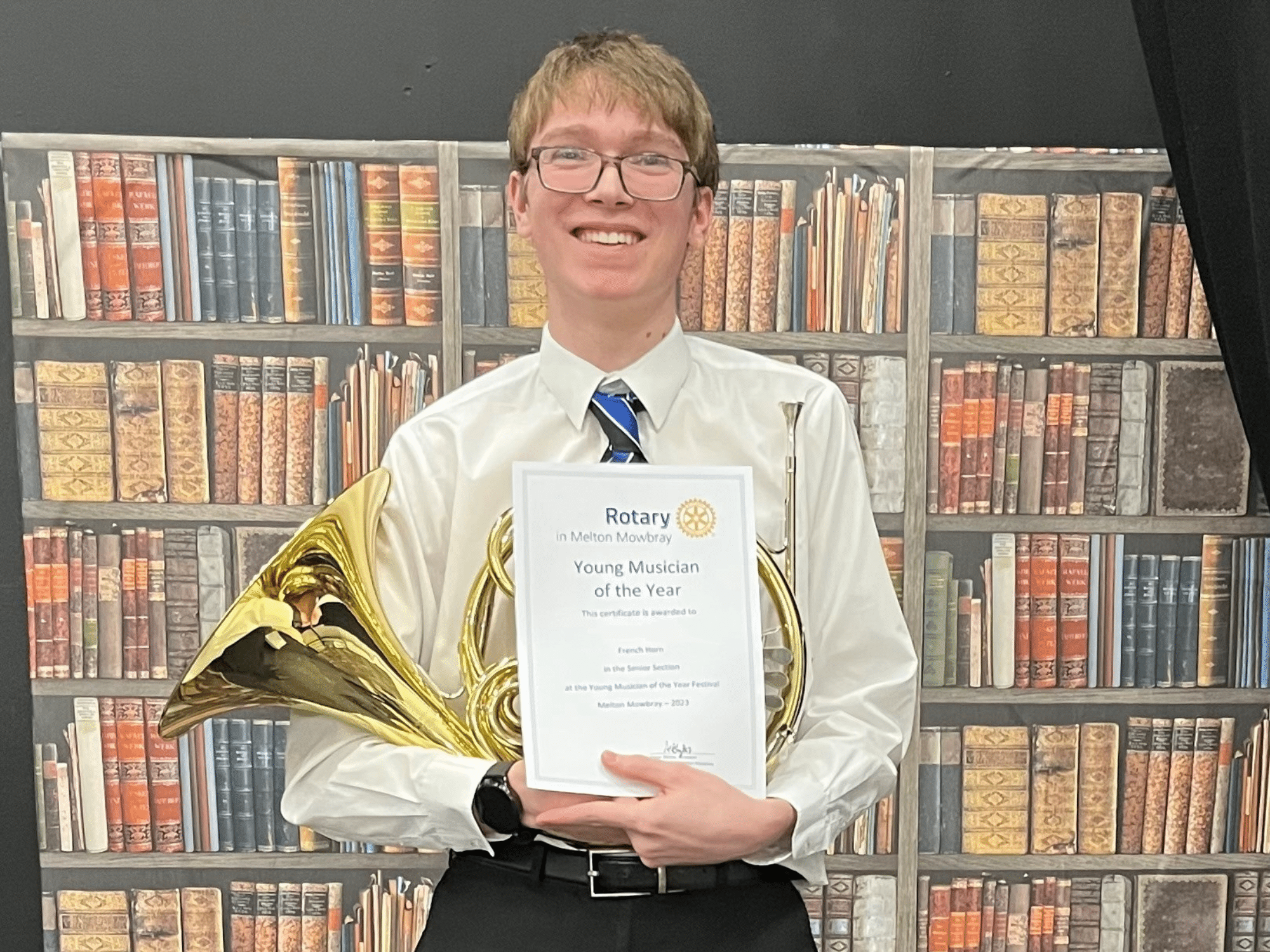 Student holds certificate for French horn performance
