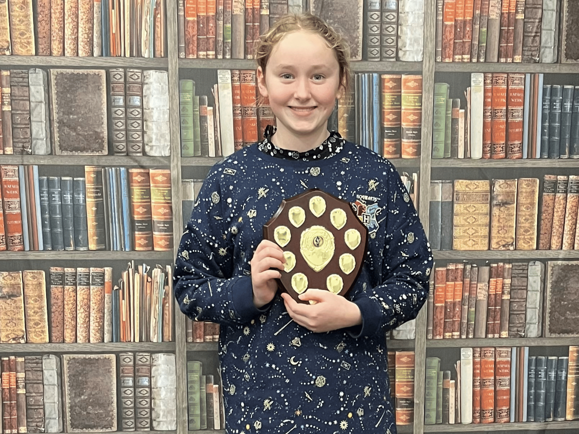 A student smiles with a shield after winning music competition