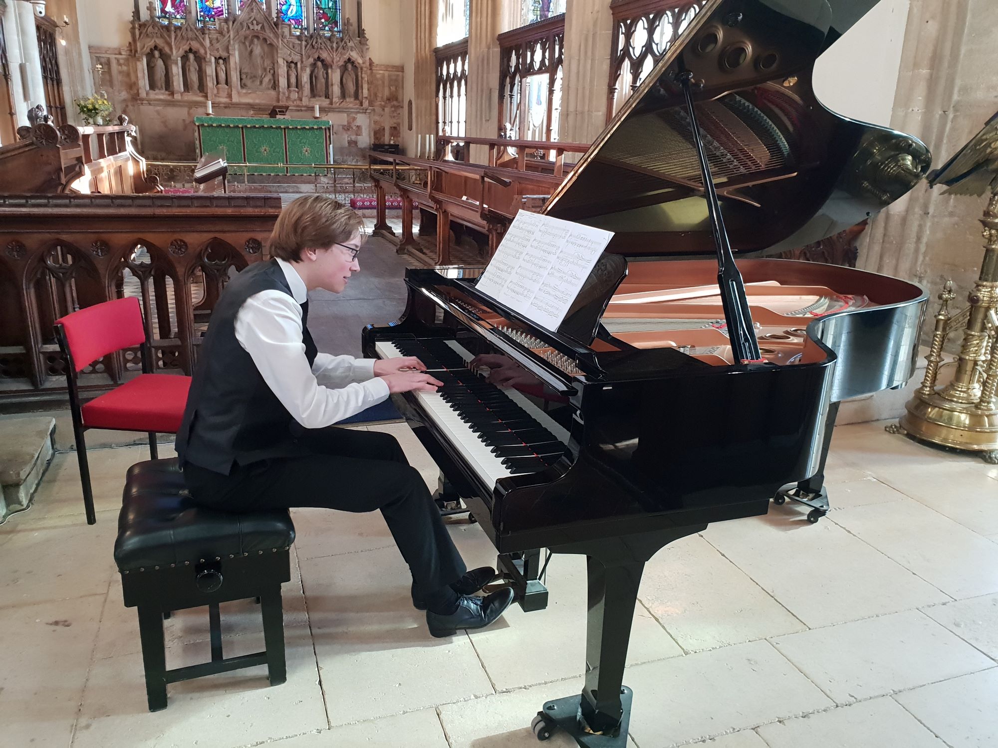 Student plays the piano in a recital in a church