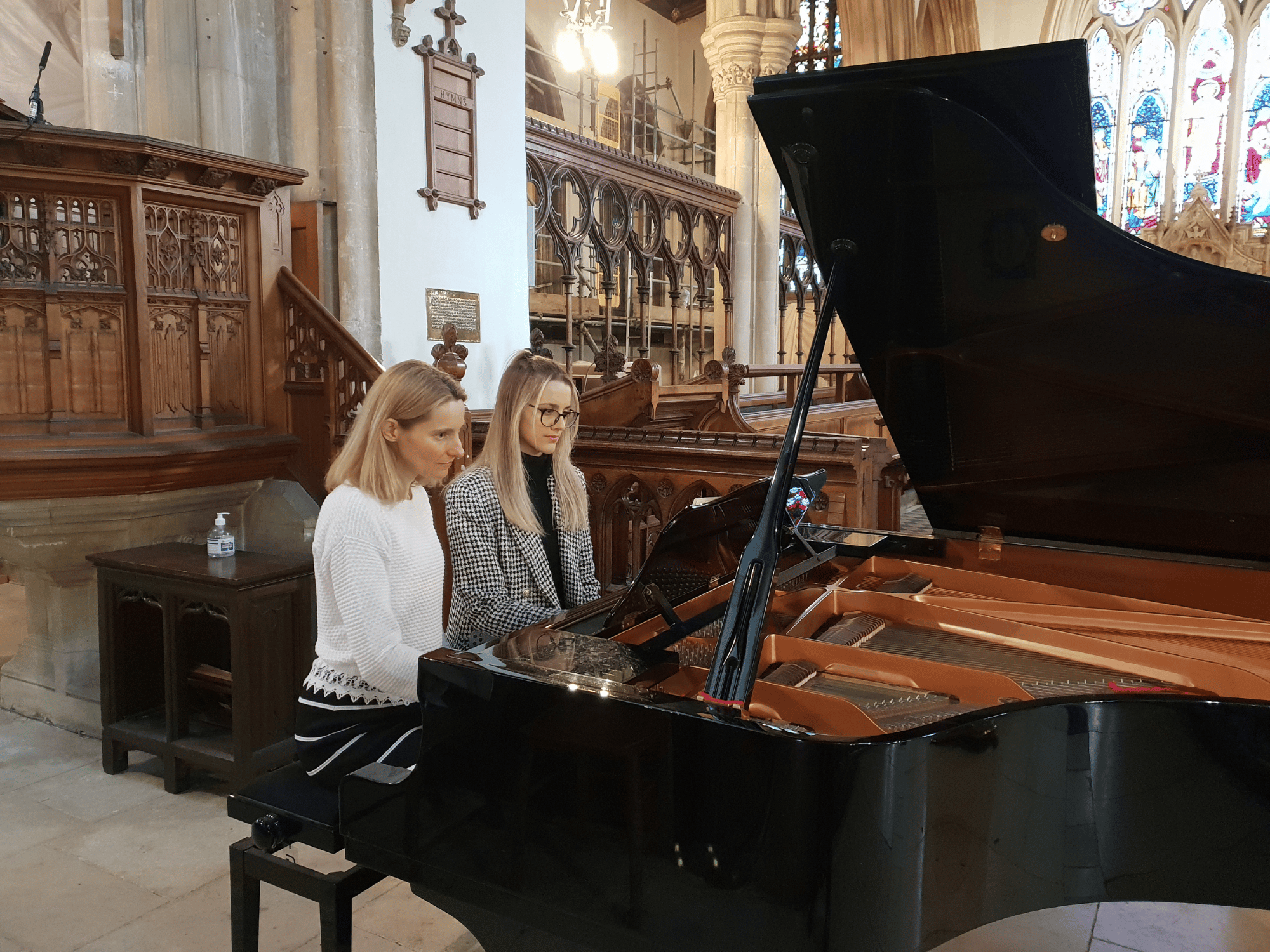 Student and teacher play piano duet in concert in a church