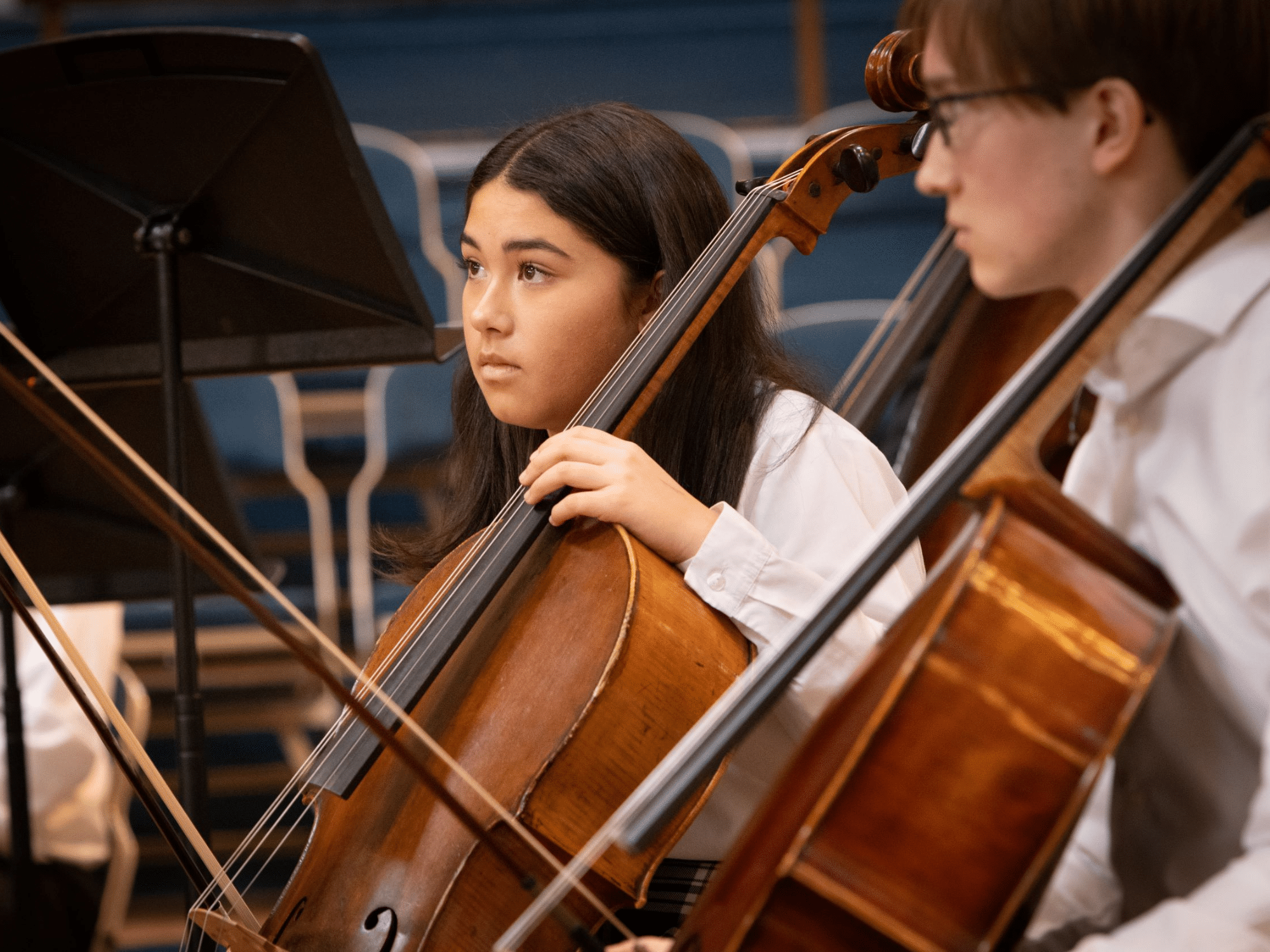Two students playing the cello in orchestra