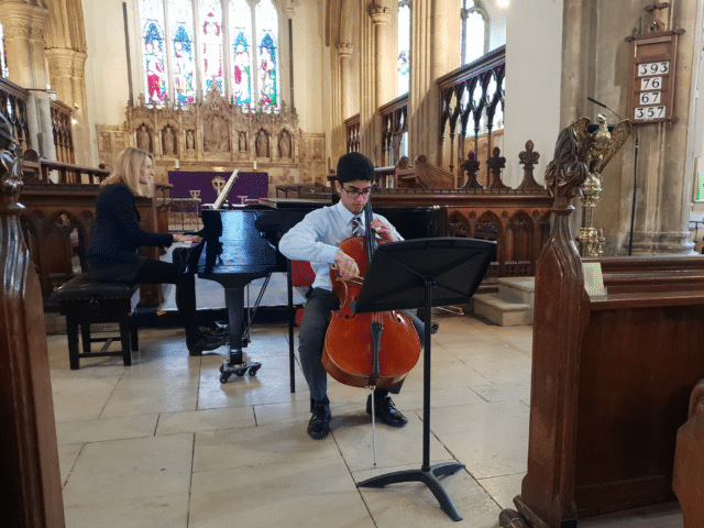 Student plays cello in a concert in church
