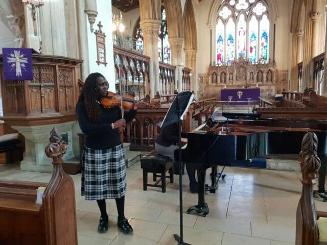 Student plays the violin in concert in a church