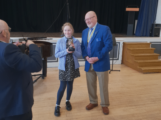 Student is awarded trophy after success in music competition