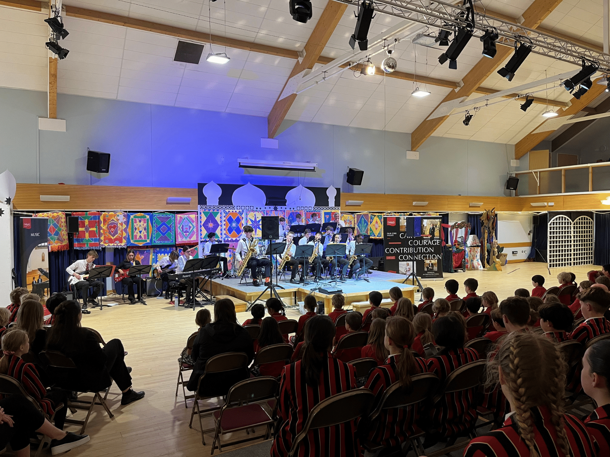 School big band perform on stage to listening students
