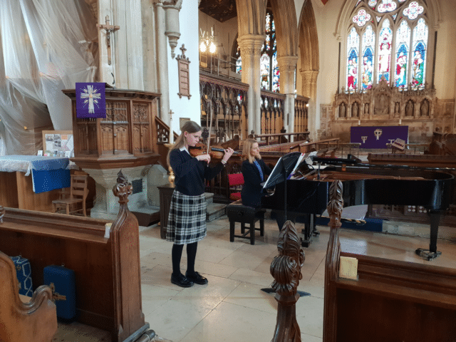 Student plays violin in church in concert