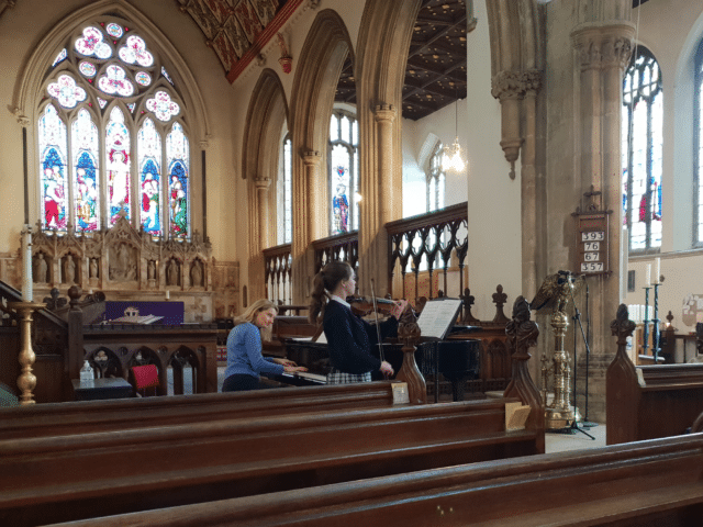 Student plays violin in church in concert