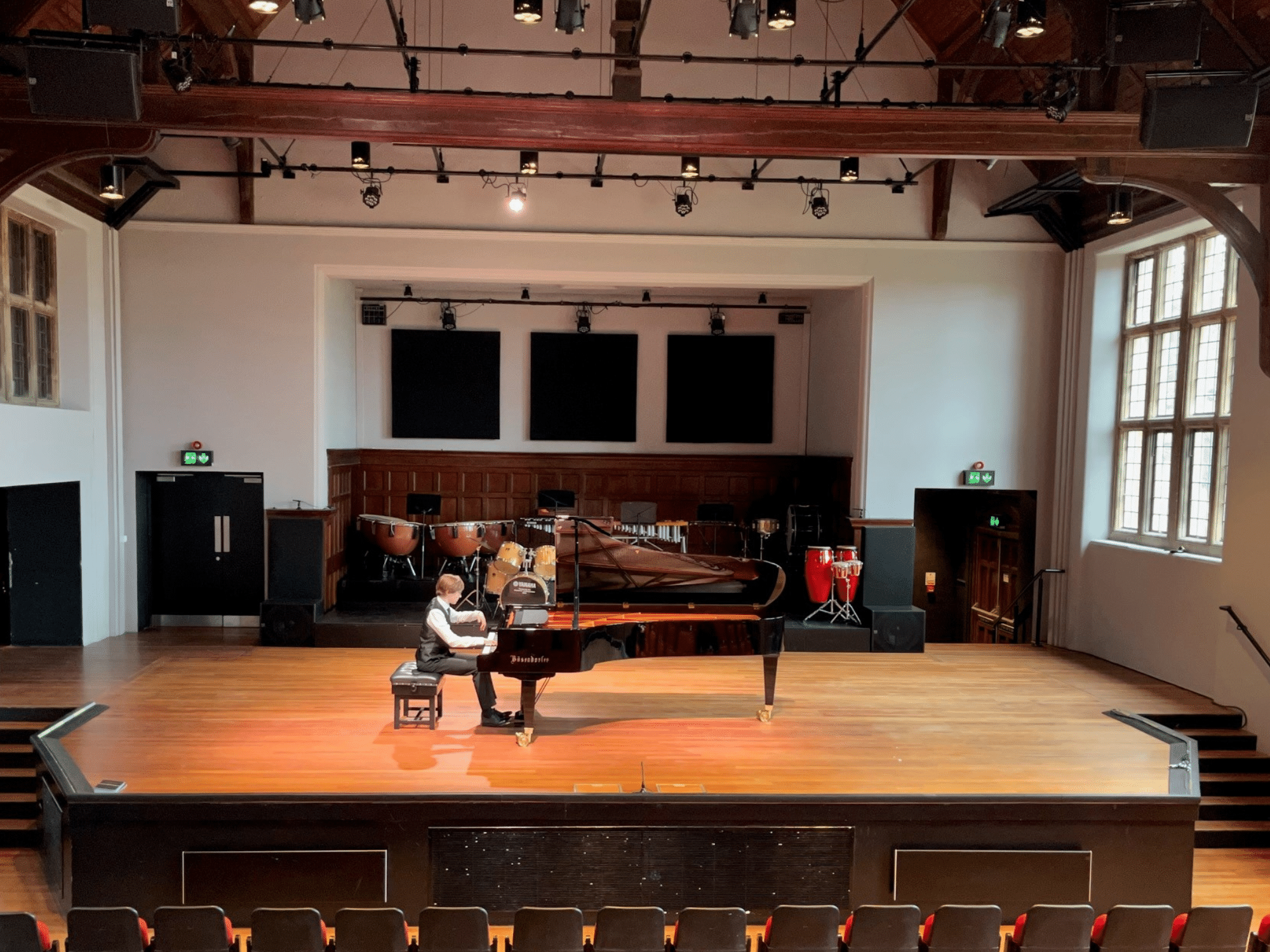 Student plays grand piano on stage in concert hall