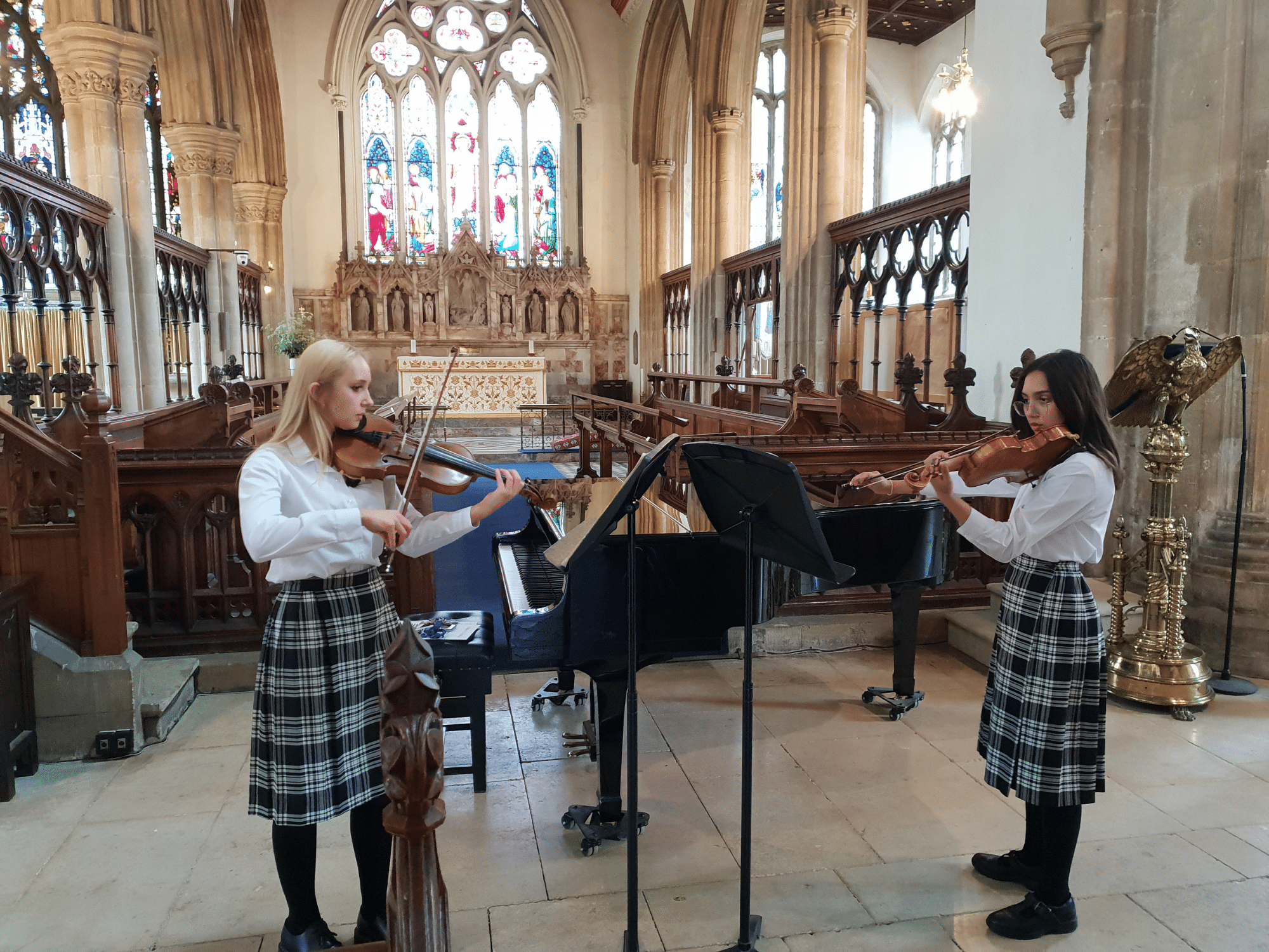 Two students play the violin in church concert