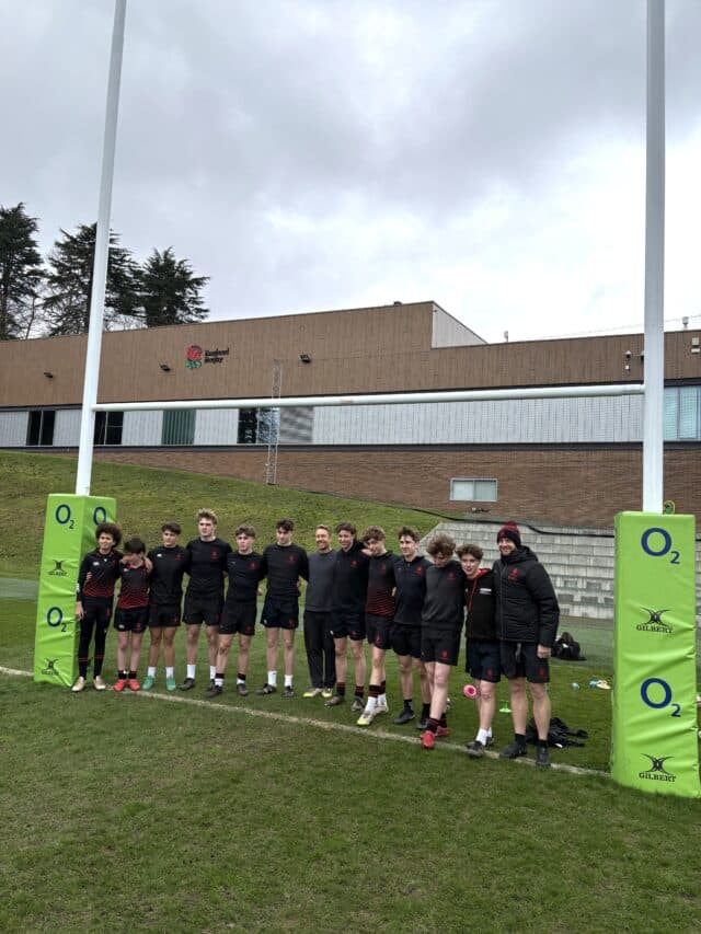 A group of rugby players with rugby legend Jonny Wilkinson standing in a line between rugby goalposts