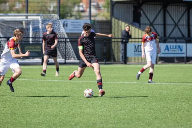 A boy in football kit kicking a football